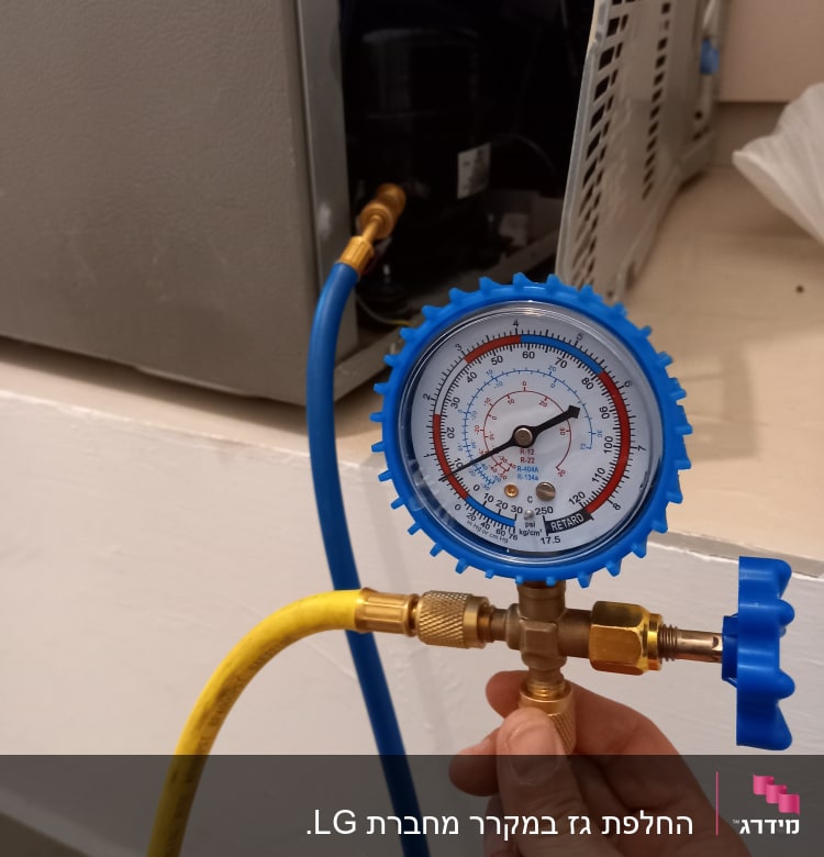 מד לחץ מחובר למקרר עם צינורות כחולים וצהובים
